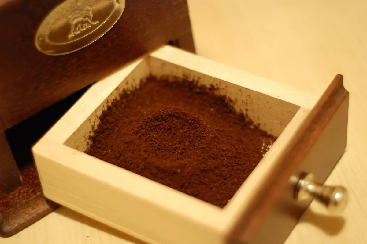 Cajón de madera de un molinillo lleno de café recién molido