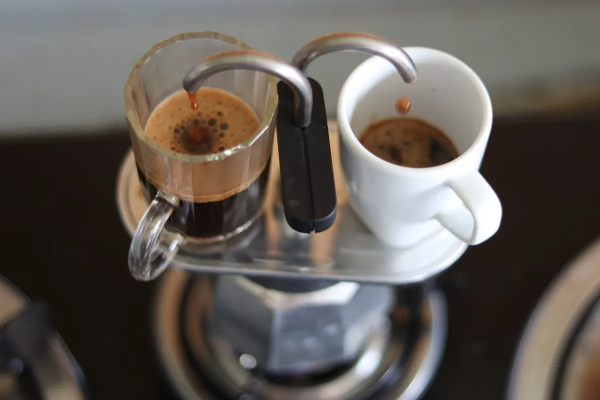 Dos espressos recién extraídos, uno en vaso de cristal y otro en taza blanca