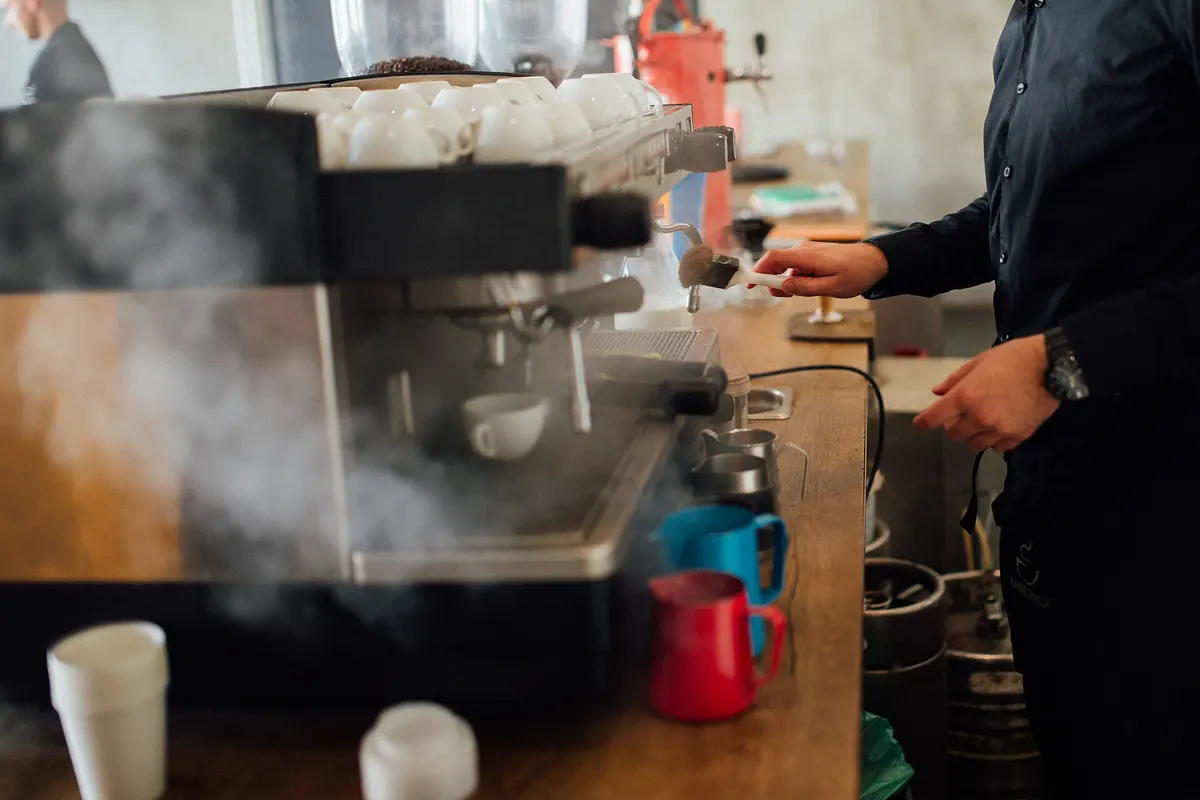 Vapor saliendo de una máquina de espresso en una barra de madera